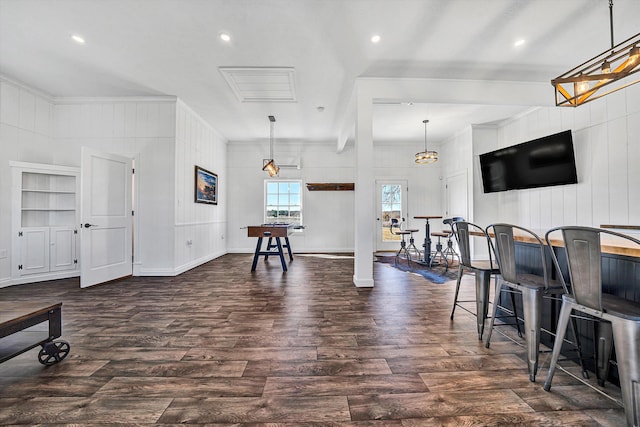 interior space featuring dark wood finished floors, hanging light fixtures, and ornamental molding