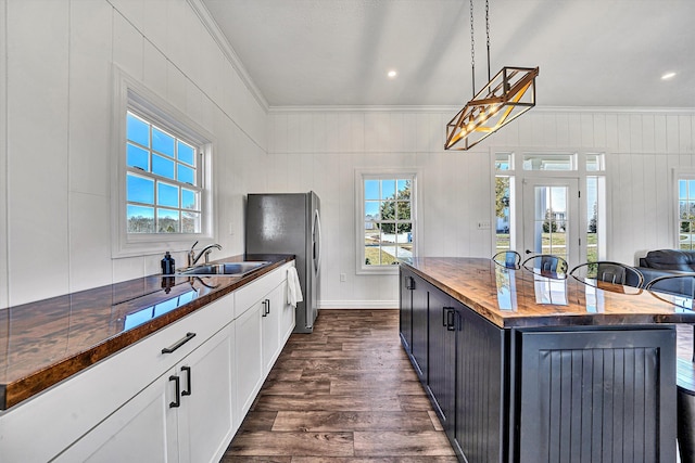 kitchen with a wealth of natural light, ornamental molding, dark wood-style floors, and wooden counters