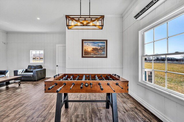 game room featuring wood finished floors, a healthy amount of sunlight, and ornamental molding