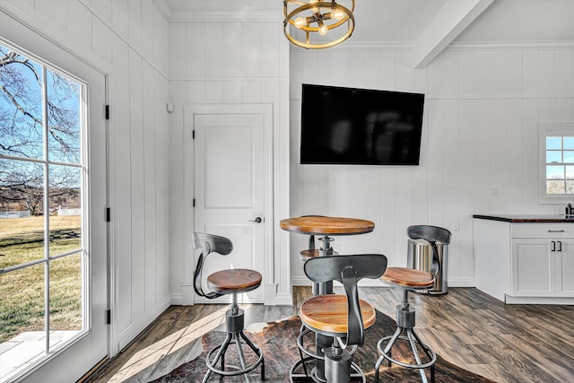 interior space featuring wood finished floors, beam ceiling, a chandelier, and crown molding