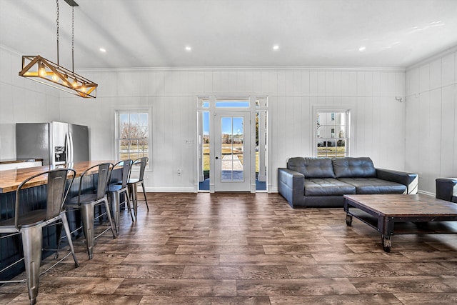 living room with dark wood finished floors, wood walls, and crown molding