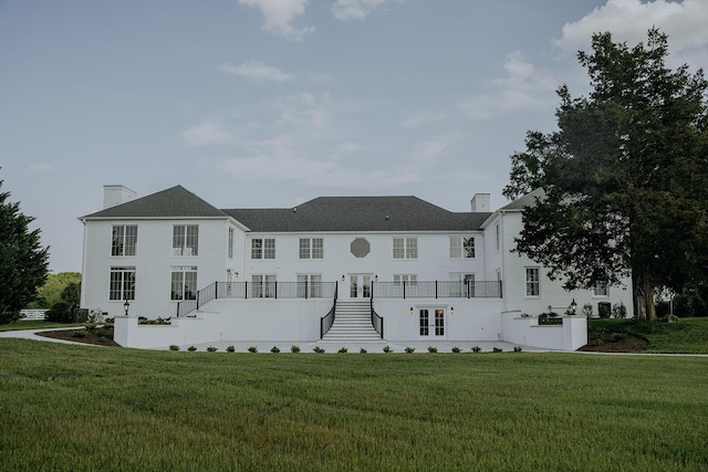 view of front facade with a front lawn, a chimney, french doors, and stairs