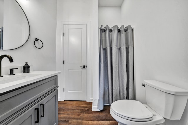 bathroom featuring a shower with shower curtain, wood finished floors, toilet, and vanity