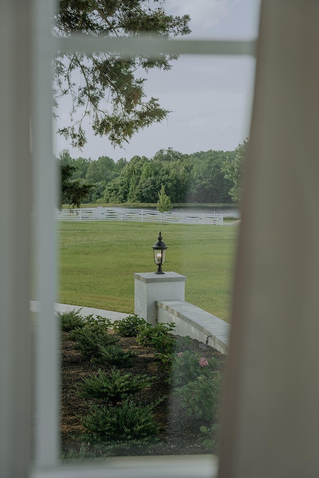 exterior space with fence, a water view, and a wooded view