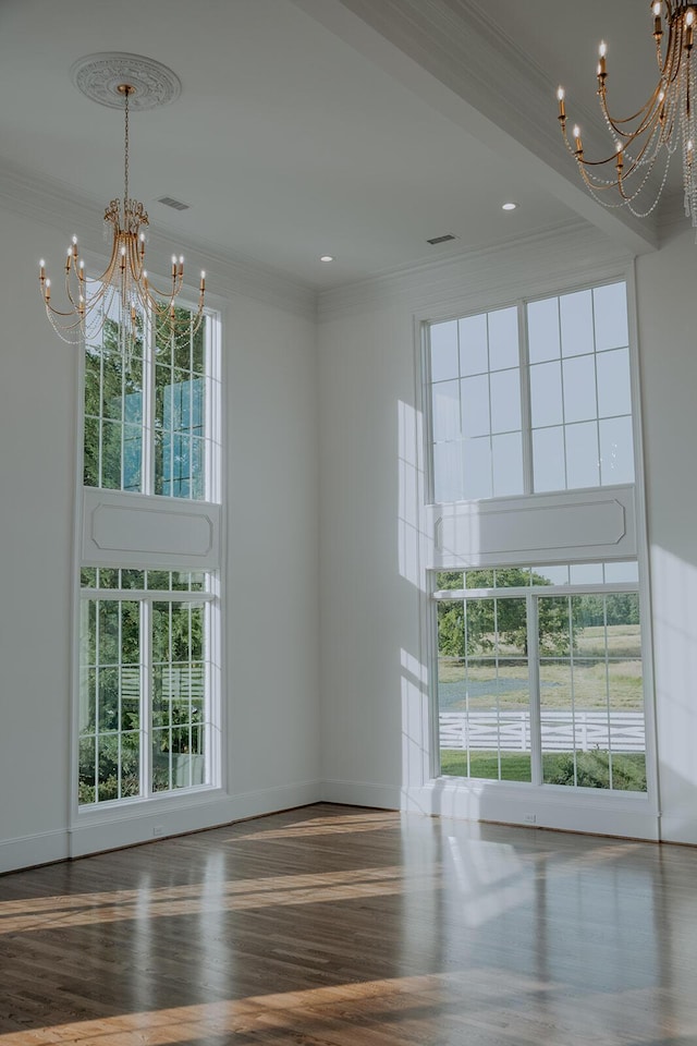 empty room featuring a notable chandelier, ornamental molding, and a healthy amount of sunlight