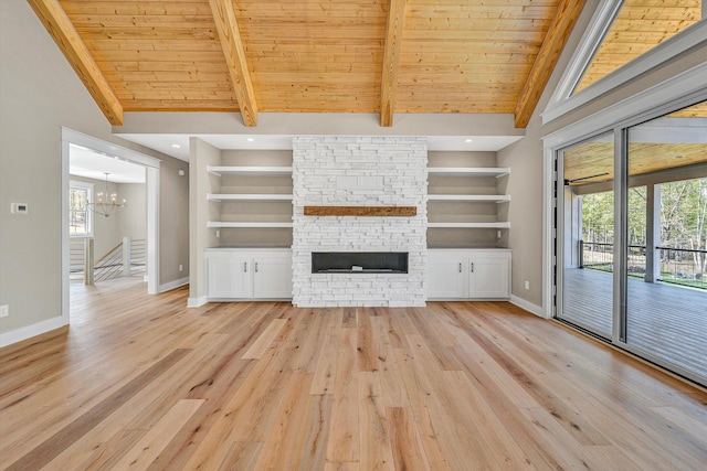 unfurnished living room with built in shelves, baseboards, light wood-type flooring, and an inviting chandelier