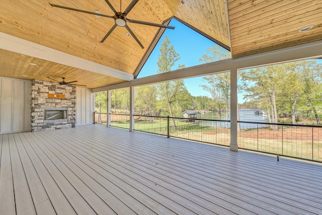 wooden deck with a ceiling fan, a fireplace, and a water view