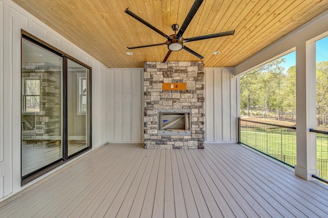 wooden deck with an outdoor stone fireplace and ceiling fan