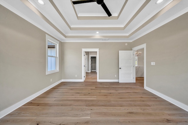 unfurnished bedroom featuring a tray ceiling, light wood-type flooring, crown molding, baseboards, and ceiling fan with notable chandelier