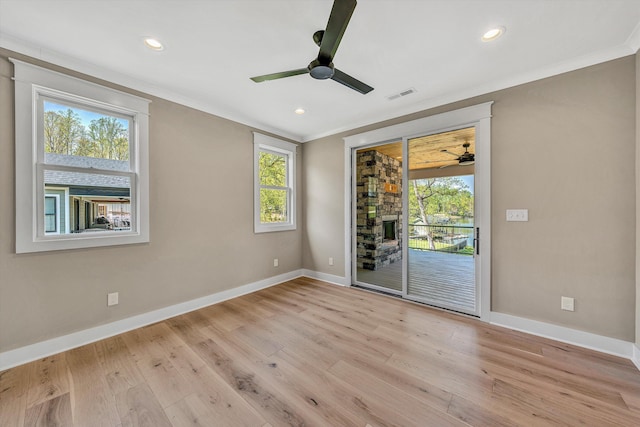 empty room with a ceiling fan, light wood finished floors, baseboards, ornamental molding, and visible vents