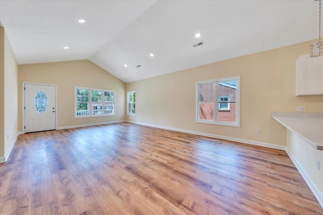 unfurnished living room with vaulted ceiling, light wood-style floors, visible vents, and baseboards