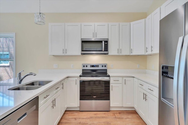 kitchen featuring white cabinetry, stainless steel appliances, light countertops, and a sink