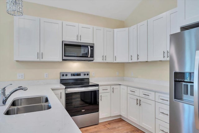 kitchen featuring white cabinets, light wood finished floors, appliances with stainless steel finishes, and a sink