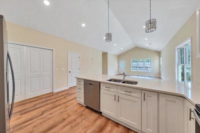 kitchen featuring lofted ceiling, light countertops, a sink, light wood-style flooring, and appliances with stainless steel finishes