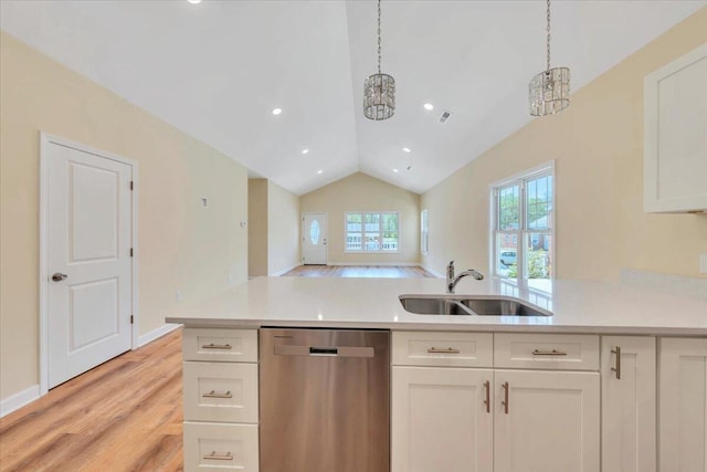 kitchen featuring light countertops, light wood finished floors, stainless steel dishwasher, and a sink