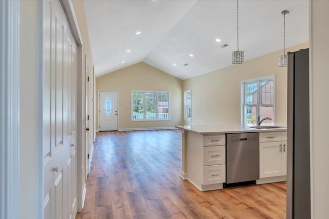 kitchen with vaulted ceiling, open floor plan, light countertops, white cabinets, and appliances with stainless steel finishes