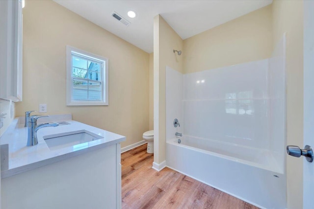 bathroom featuring a sink,  shower combination, toilet, visible vents, and wood finished floors