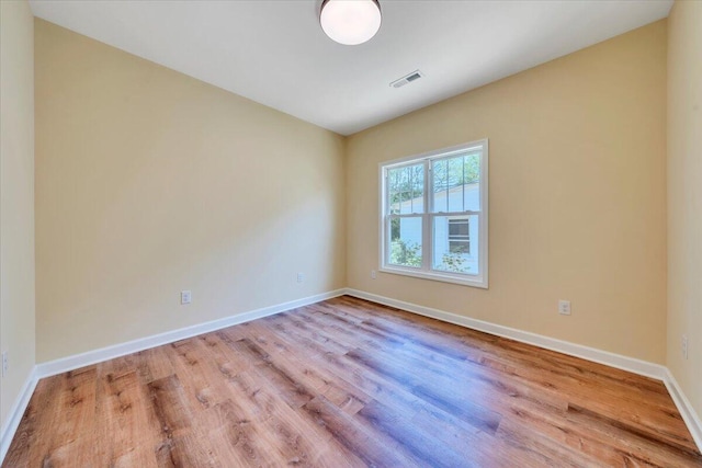 empty room featuring visible vents, baseboards, and wood finished floors