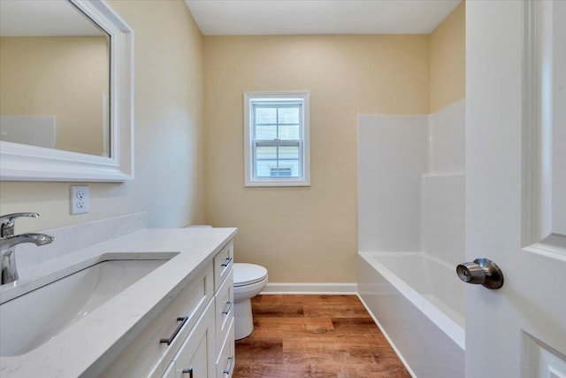 bathroom featuring toilet, shower / bathing tub combination, baseboards, wood finished floors, and vanity