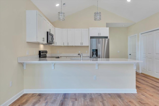 kitchen with stainless steel appliances, a peninsula, a kitchen breakfast bar, a sink, and light countertops
