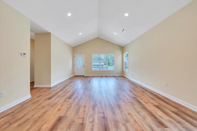 unfurnished living room with vaulted ceiling, light wood-style floors, visible vents, and baseboards