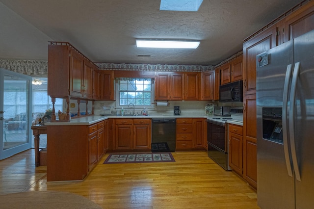 1615 Deyerle Rd SW, Roanoke, VA 24015 - kitchen featuring black appliances, light wood-type flooring, brown cabinets, and a textured ceiling
