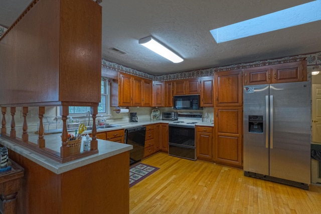 1615 Deyerle Rd SW, Roanoke, VA 24015 - kitchen featuring black appliances, light countertops, brown cabinets, light wood-type flooring, and a textured ceiling