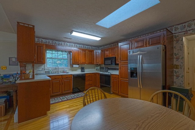 1615 Deyerle Rd SW, Roanoke, VA 24015 - kitchen with black appliances, wallpapered walls, a sink, light wood-style flooring, and light countertops