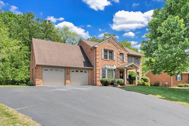 view of front of property featuring brick siding, an attached garage, driveway, and a front lawn