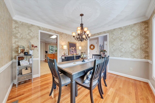 dining area with crown molding, wallpapered walls, light wood finished floors, and a chandelier