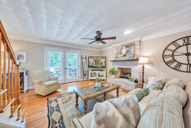 living area with ornamental molding, a ceiling fan, stairs, and wood finished floors