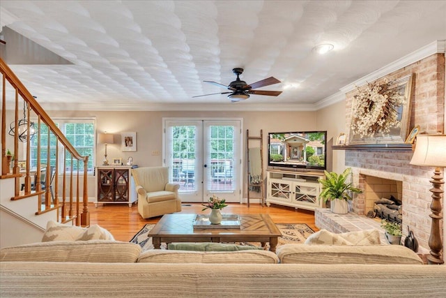 living room with crown molding, stairs, wood finished floors, a fireplace, and a ceiling fan