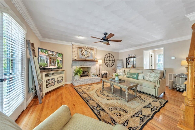 living area with crown molding, a brick fireplace, ceiling fan, and wood finished floors