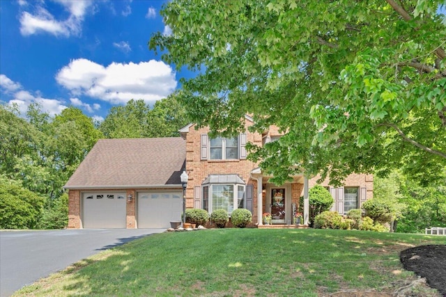 view of front of home featuring a garage, a front yard, aphalt driveway, and brick siding