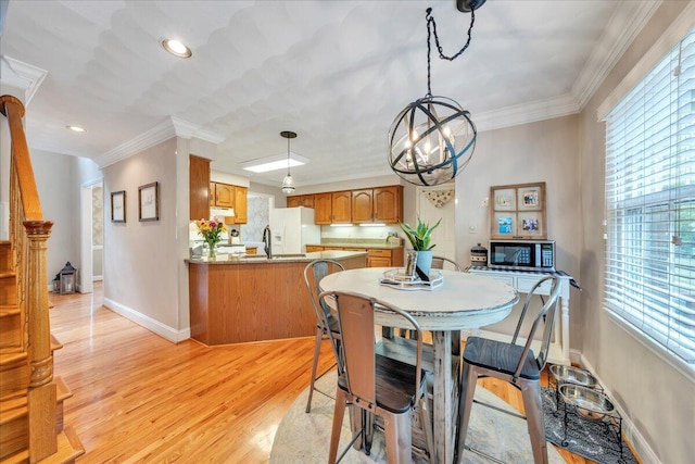 dining space with a healthy amount of sunlight, baseboards, light wood-style flooring, and a chandelier