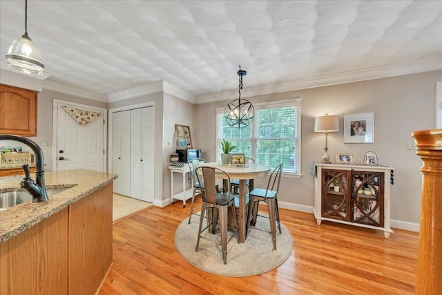 dining area featuring light wood-style floors, baseboards, crown molding, and a notable chandelier