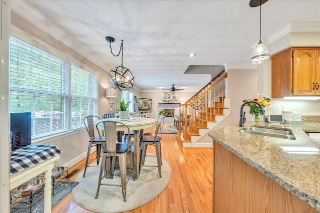 dining space featuring stairs, plenty of natural light, ornamental molding, and light wood finished floors