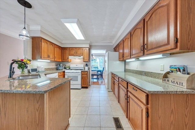 kitchen with brown cabinetry, a peninsula, white appliances, under cabinet range hood, and a sink