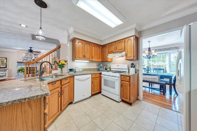 kitchen featuring light stone countertops, a sink, a peninsula, under cabinet range hood, and white appliances