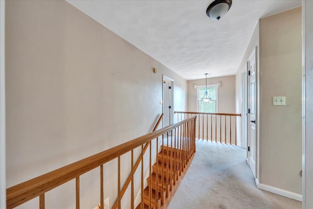 corridor featuring carpet flooring, baseboards, and an upstairs landing