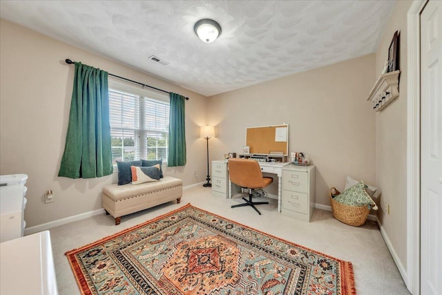 carpeted office with a textured ceiling, baseboards, and visible vents