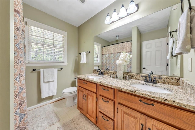 bathroom with double vanity, a sink, tile patterned floors, and toilet
