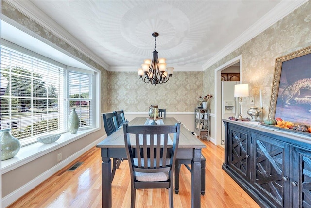 dining room with visible vents, ornamental molding, wallpapered walls, a chandelier, and light wood finished floors