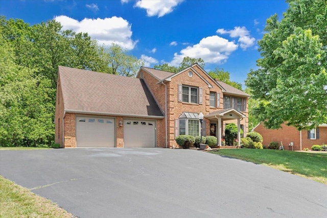 view of front of house featuring an attached garage, a front yard, driveway, and brick siding
