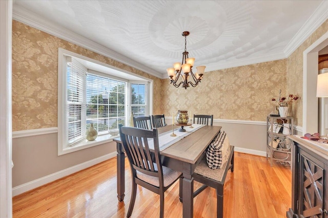 dining space with light wood-style floors, ornamental molding, a chandelier, and wallpapered walls