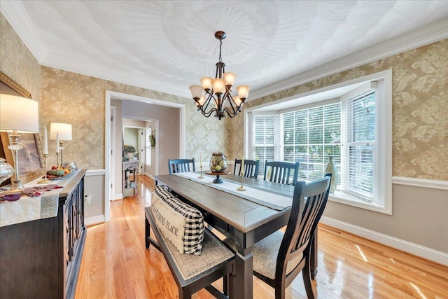 dining room with wallpapered walls, an inviting chandelier, ornamental molding, and light wood-style flooring