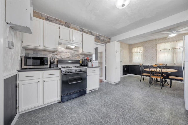kitchen with range with gas cooktop, stainless steel microwave, under cabinet range hood, and white cabinetry
