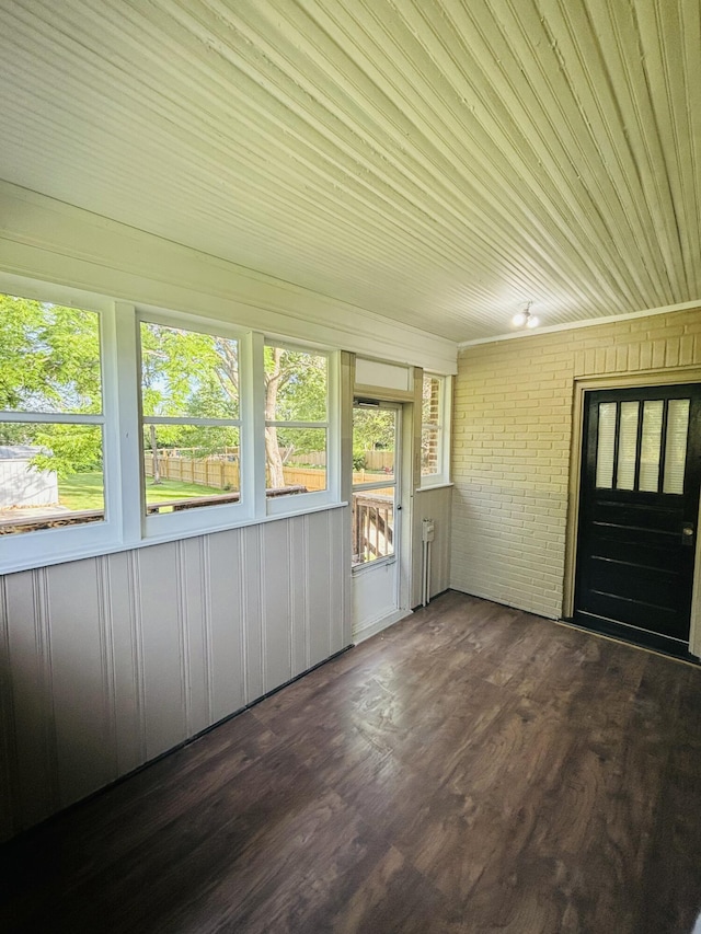 unfurnished sunroom with brick wall and wood finished floors