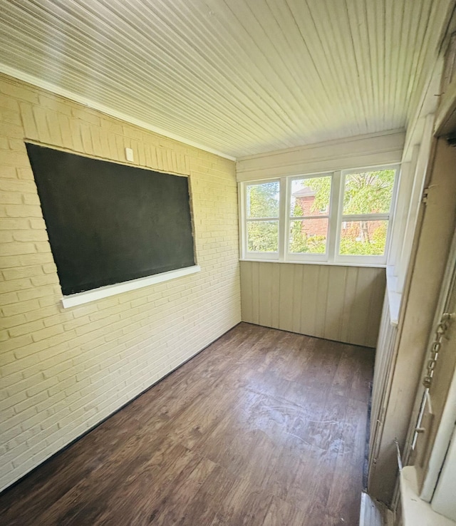 unfurnished sunroom featuring wood finished floors and brick wall