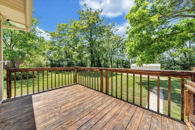 wooden deck featuring a yard, a storage shed, an outdoor structure, and view of wooded area